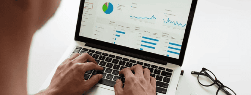 Persoon werkt aan laptop met grafieken Rapportages maken met Fenna vrijwilligerssoftware